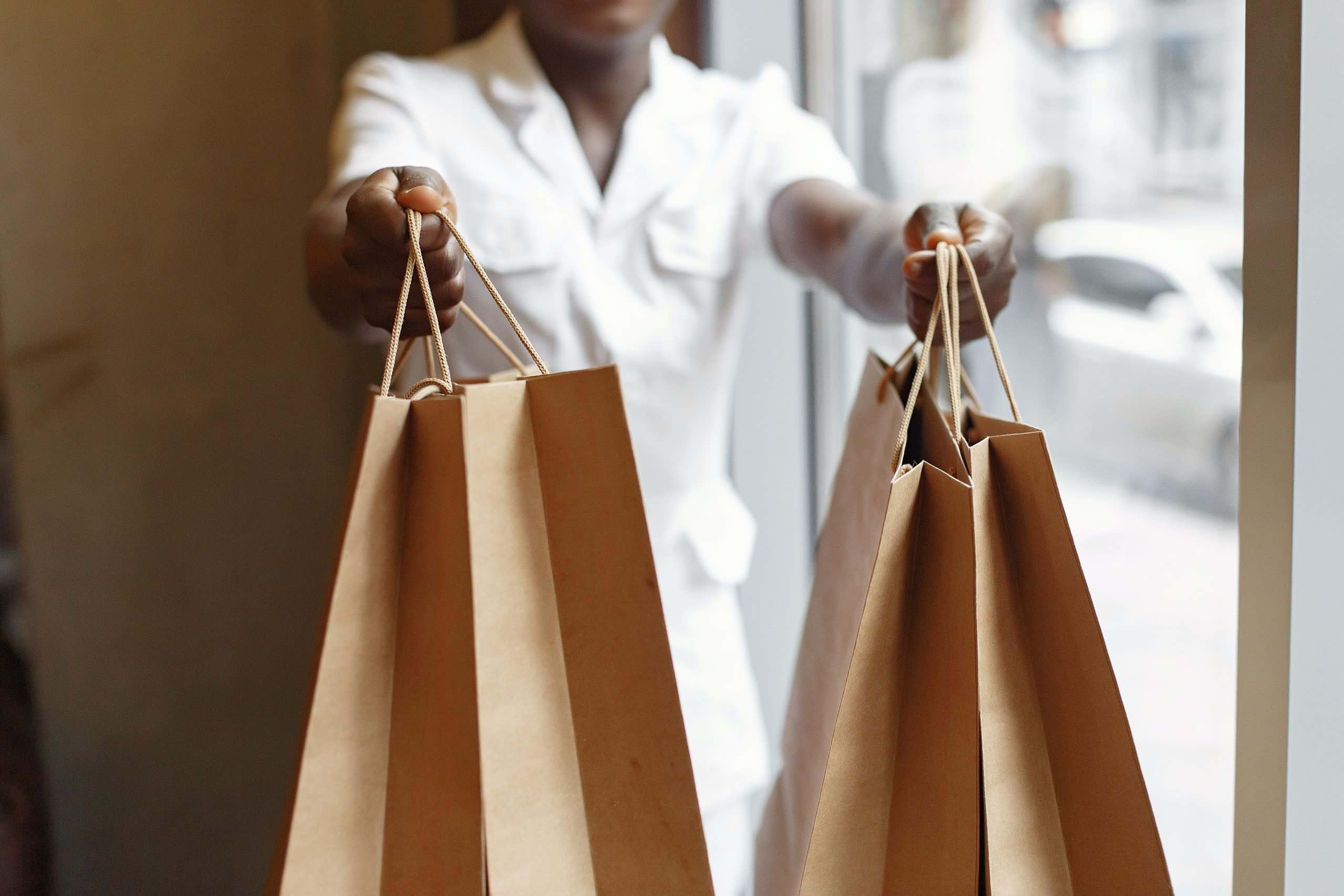 Een afbeelding van iemand die tassen overhandigd met kleding die gekocht is.