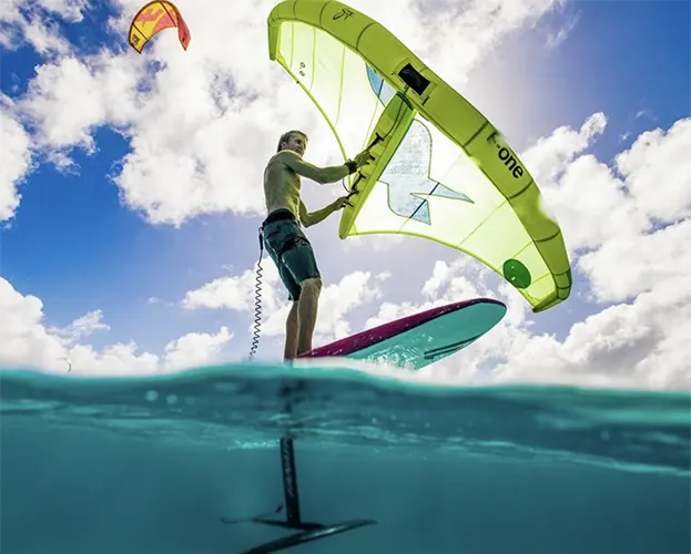 Persoon die op Bonaire aan het wingfoilen is, wat de opwinding van de sport laat zien. Huur materiaal of neem lessen bij onze partner en geniet van speciale kortingen op pick-up verhuur bij Pickup Huren Bonaire.